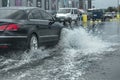 Driving car on flooded road during flood caused by torrential rains. Cars float on water, flooding streets. Splash on the car.