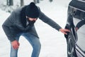 Driving a car in winter. Man checks wheels on a snowy road before driving