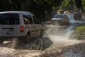 Driving cars on a flooded road during floods caused by rain storms. Cars float on water, flooding streets. Splash on the machine.