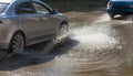 Driving cars on a flooded road during floods caused by rain storms. Cars float on water, flooding streets. Splash on the machine.