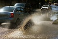 Driving cars on a flooded road during floods caused by rain storms. Cars float on water, flooding streets. Splash on the machine.