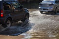 Driving cars on a flooded road during floods caused by rain storms. Cars float on water, flooding streets. Splash on the machine.