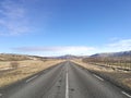 Driving on empty open asphalt road towards range of mountains covered in snow on blue sky sunny day, business success and way forw Royalty Free Stock Photo