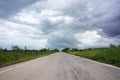 Driving on an empty road. Empty asphalt road through the green field and clouds on rainstorm in rainy season. Open road ahead, end Royalty Free Stock Photo