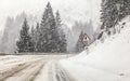 Driving through heavy snowstorm / blizzard on forest road, view from car behind. Snow on ground makes everything slippery - Royalty Free Stock Photo