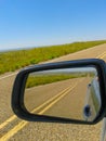 Driving on long straight highway with view ahead, and behind in reavision mirror Royalty Free Stock Photo