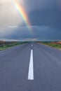 Driving om empty road under the rainbow Royalty Free Stock Photo