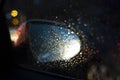 driving at rainy night. reflection of rain drops at the car side mirror. city lights at night Royalty Free Stock Photo