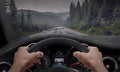 Driving in rainy weather. View from the driver angle while hands on the wheel. Rain splashed windshield Royalty Free Stock Photo