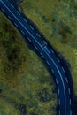 Driving on a road through the green mossy river water in Iceland, aerial, vertical