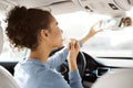 Driving safety concept. Afro woman doing makeup in car