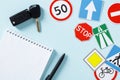 Driving school test concept. Blank paper notebook, pen, car keys, road signs and traffic symbols on color background Royalty Free Stock Photo