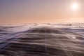 Driving snow flows across the road, almost obscuring it during heavy winds in Southern Iceland