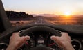 Driving at sunset. View from the driver angle while hands on the wheel