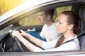 Driving test. Young woman driving a car, man sitting aside Royalty Free Stock Photo