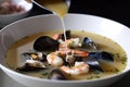 drizzle of extra virgin olive oil over bowl of seafood soup
