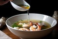 drizzle of extra virgin olive oil over bowl of seafood soup