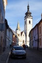 Drlicov Street, view of the sunlit Church of the Nativity of the Blessed Virgin Mary in the perspective, Pisek, Czechia