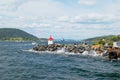 People enjoy the view to the fjord from a lighthouse at the entrance to the harbor in Drobak, Norway.