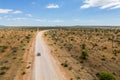 Drone image of offroad vehicle driving on dirt road in African bush