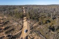 Drone aerial photograph of a truck driving on a dirt road in a forest