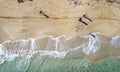 Drone aerial scenery of unrecognised people walking in a sandy beach in winter. Windy waves crashing on the shore
