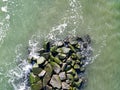 Drone aerial view directly over a rock jetty with ocean water pounding thee boulders
