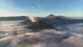 Aerial view fly pass hill to reveal Bromo volcano in a background, Indonesia