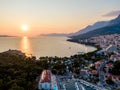 Drone aerial view of Makarska city, Croatia. Sunset over the city, beach and se. Biokovo mountains in the background. Summer time Royalty Free Stock Photo