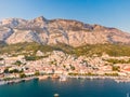 Drone aerial view of Makarska city, Croatia. Sunset over the city, beach and se. Biokovo mountains in the background. Summer time Royalty Free Stock Photo