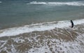 Drone aerial of young boy in shorts standing on beach and looking at the waves. View from the back. Stormy weather on the sea Royalty Free Stock Photo