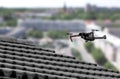 Drone in the air inspecting the roof over the house. Close-up of drone and roof Royalty Free Stock Photo