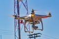 Drone with camera flying with antenna , pole, electricity wires and blue sky in the background Royalty Free Stock Photo