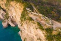 Drone with camera rises above ruins of Mogren fortress in Budva, Montenegro, surrounded by forest and road, which is