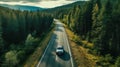 A drone captures a car driving along a highway nestled within a forest