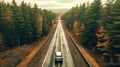 A drone captures a car driving along a highway nestled within a forest