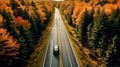 A drone captures a car driving along a highway nestled within a forest