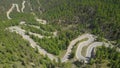 DRONE: Cars and motorbikes drive along the hairpins winding through the woods.
