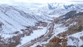 DRONE: Cars and trucks move down scenic highway leading towards snowy mountains