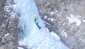 DRONE: Woman carefully placing her ice axes while climbing up an icy waterfall Royalty Free Stock Photo