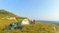 DRONE: Cheerful tourists mountain biking in the Alps preparing a tent in meadow. Royalty Free Stock Photo