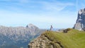 DRONE: Cheerful woman hikes up to the edge of grassy hill and outstretches arms.