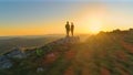 DRONE: Cinematic shot of active young couple observing the evening landscape.