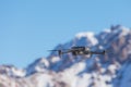 Drone with digital camera flying over winter landscape with snow covered mountains and trees. White remote controlled Royalty Free Stock Photo