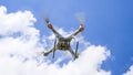 Drone DJI Phantom 4 in flight. Quadrocopter against the blue sky with white clouds. The flight of the copter in the sky Royalty Free Stock Photo