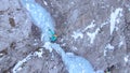 DRONE: Female climber placing her ice-picks while climbing up an icy waterfall. Royalty Free Stock Photo