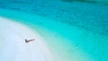 DRONE: Flying above female tourist in bikini lying on the beach and sunbathing. Royalty Free Stock Photo