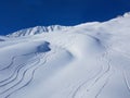 DRONE: Flying above snowboarding and ski tracks left in the deep powder snow. Royalty Free Stock Photo