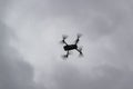 Drone flying in grey sky with clouds in the background. Silhouette of drone flying in cloudy grey sky Royalty Free Stock Photo