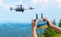 Drone flying in natural landscape while the pilot operates the controller and monitors the live video feed for filming or mapping Royalty Free Stock Photo